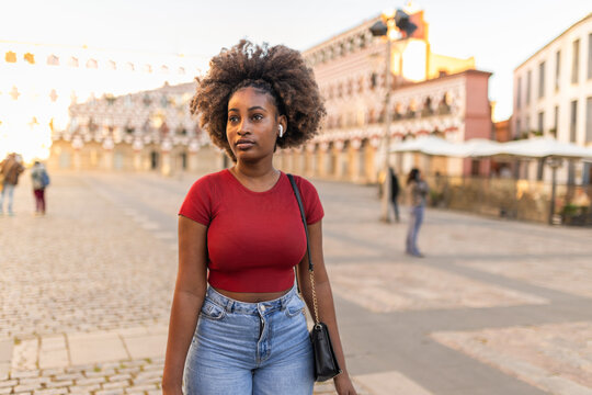 Portrait of a smiling black woman with afro hair in a city square