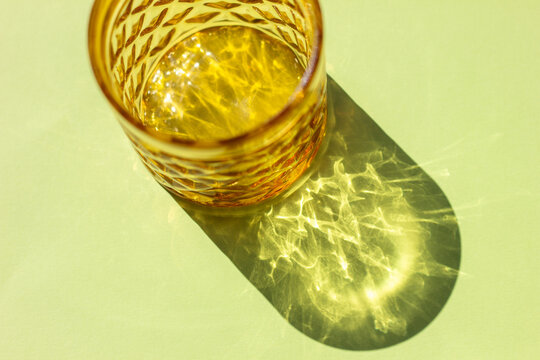 Amber Glass with Sunlit Caustic Reflections on Green Background