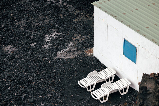Minimal beach hut and loungers on black lava coast
