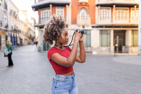 A black woman explores the city and takes photographs.
