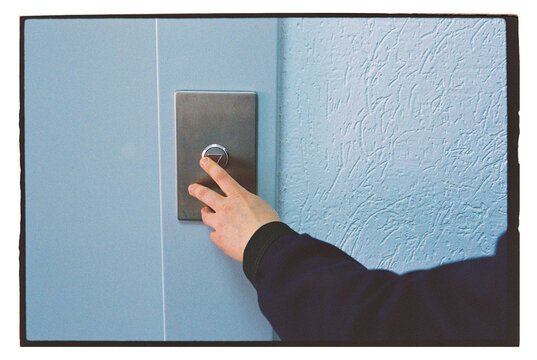 Hand pressing elevator button in a building