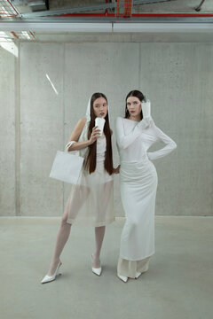 Stylish women shoppers drinking soda through straws with shopping bags