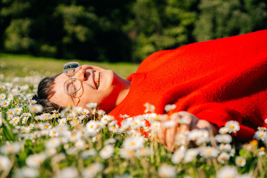 Person Lying on Grass Field Full of Flowers While Enjoying Sunlight