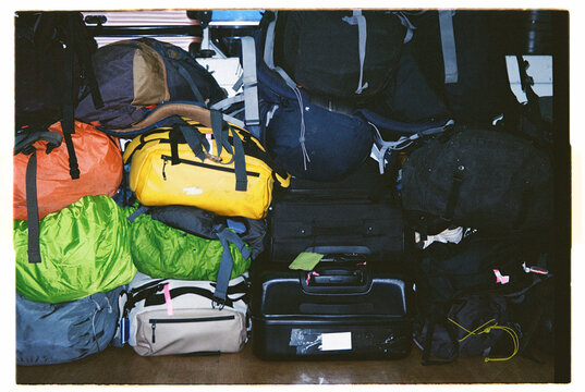 Numerous bags stacked in a corner, showing travel gear in a busy area