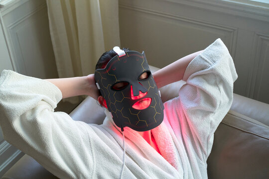 Woman Uses a Light Therapy Mask at Home in the Morning