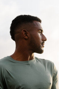 Black man in a green T-shirt, looking away with assured expression