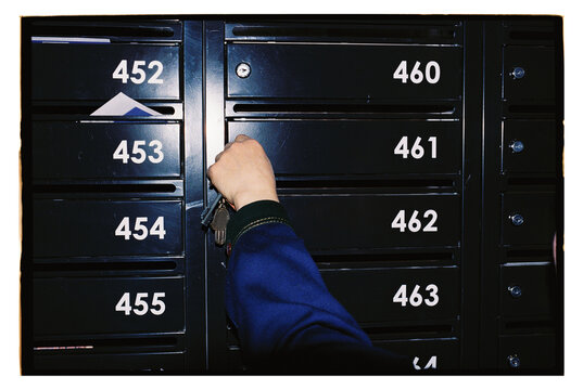 A hand opens a mailbox.