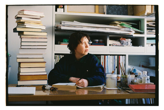 An artist sits in his studio with art supplies.