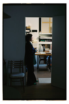 Artist stands in studio with art supplies