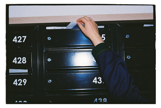 A hand takes a receipt from a mailbox