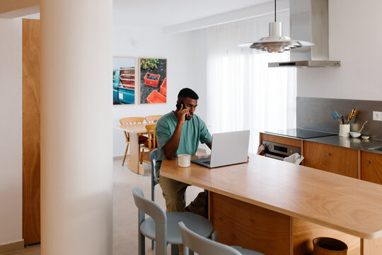 Freelancer answering business calls from his kitchen