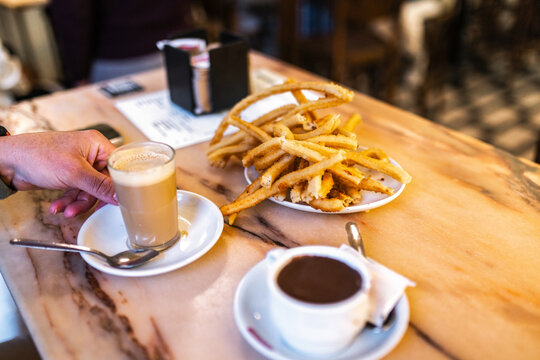 Image of a man's hands picking up a coffee on a cafe table