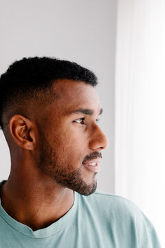 Modern Black man pauses from remote work, looking out apartment window