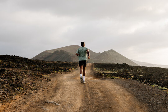Distant rear wide-angle view shows a trail athlete running