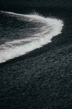 Wave washing black volcanic sand in Puntalarga Beach, La Palma