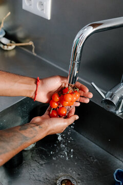 Unidentified person's hands washing cherry tomatoes