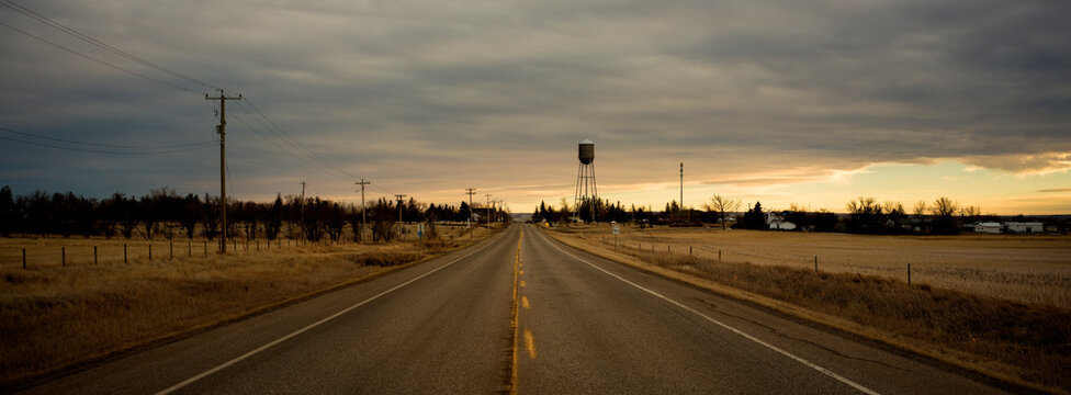 Wide Road Leading to a Distant Water Tower Under Cloudy Sky