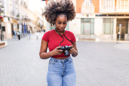 A black woman explores the city and takes photographs.