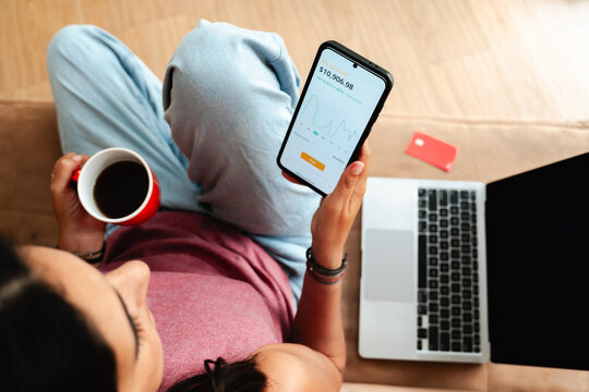 Young Person Checking Investment App on Smartphone at Home