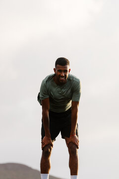 Trail runner leaning on his knees, resting