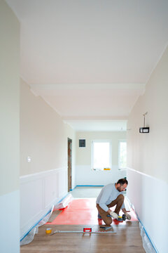Man working on floor installation in hallway