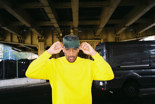 Urban man in a yellow sweatshirt is standing under an overpass