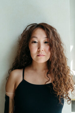 Woman With Curly Hair in a Minimalist Setting Exuding Confidence