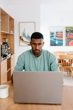 An entrepreneur focuses on tasks on a computer while sipping coffee