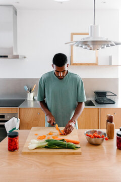 A man balances working remotely at home while also cooking