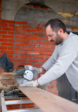 Man uses saw to cut wood in workshop
