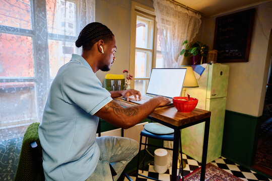 Young Black Man Working on Laptop at High Table in Kitchen