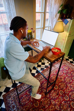 Young Black Man Working on Laptop at High Table in Kitchen