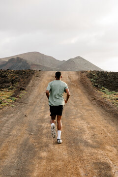 A trail athlete moving along a dirt track during training