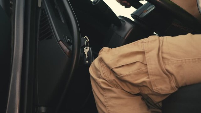 Professional driver turning ignition key to start car engine