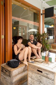 Couple sitting outside coffee shop in summer