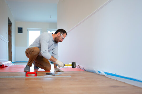 Worker repairs wall in a home during the day