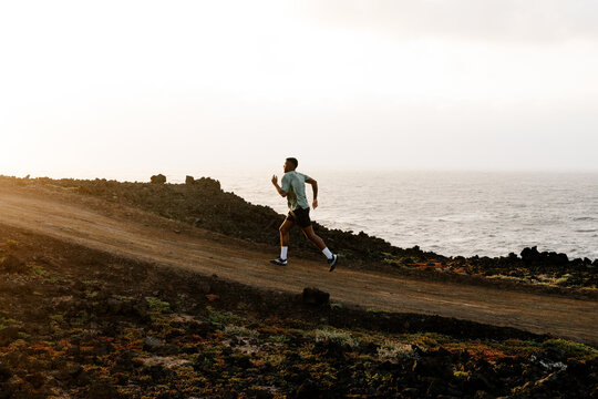 Wide view of a trail athlete training far away on a coastal dirt track