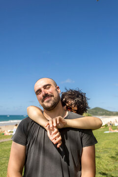 Woman embracing man from behind under blue sky at Main Beach Byron Bay