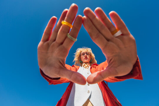 Low angle portrait of woman framing view with hands