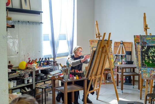 Elderly woman learning to draw in the workshop