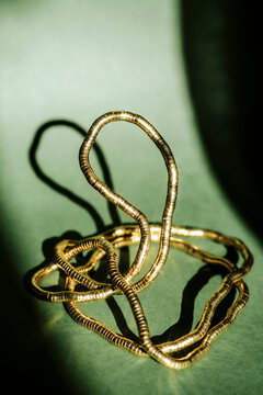 Metal Wire Sculpture on Green Paper Surface With Light Shadows