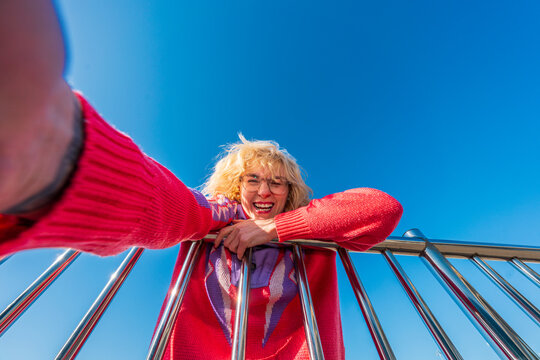 Playful woman leaning over railing reaching toward camera