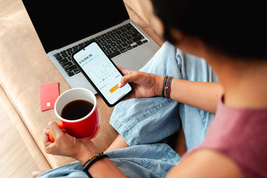 Young Person Managing Investments on Smartphone and Laptop at Home