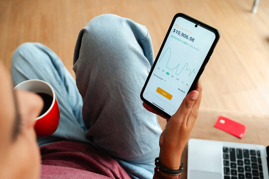 Young Person Checking Investment App on Smartphone at Home