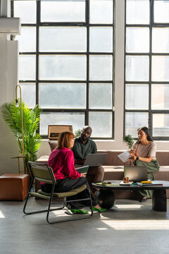 Business Team Meeting In Industrial Studio Lounge With Laptops