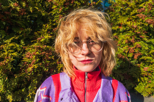 Woman with windblown hair and glasses in colorful sweater