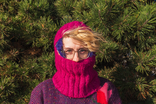 Woman in pink knitted balaclava and glasses in sunlight