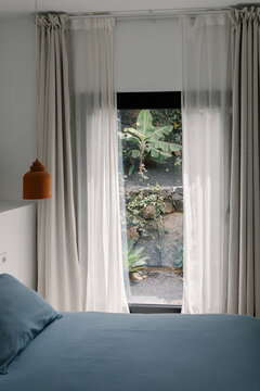 A bedroom window bathed in direct sunlight in a minimalist home