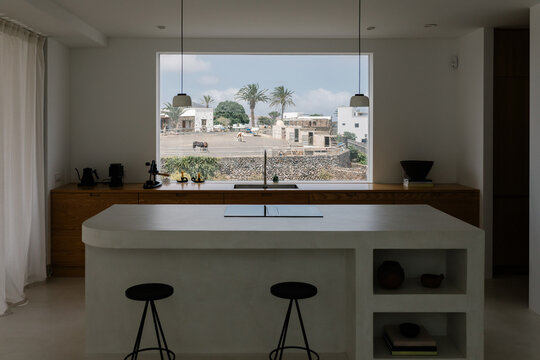A modern kitchen appears framed by a large window