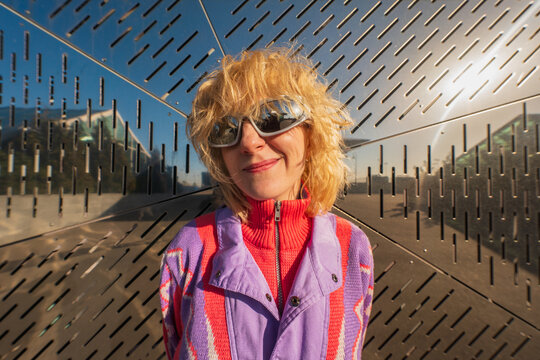 Smiling woman in sunglasses against modern perforated wall